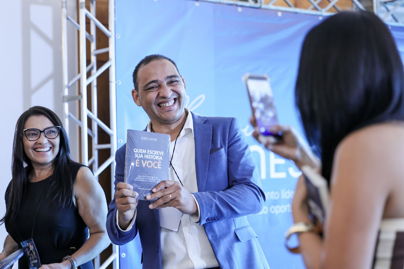 Participante exibe o livro autografado enquanto é fotografado