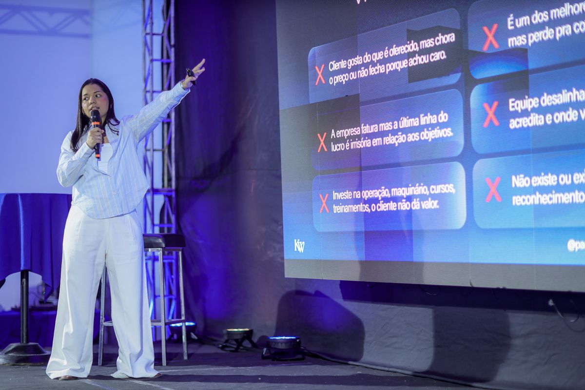 Paula Araújo apontando para o telão durante a palestra